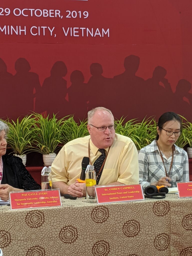 Dr. Andrew Campbell speaks at a conference in Ho Chi Minh City, Vietnam, surrounded by colleagues and discussing sustainable leadership.
